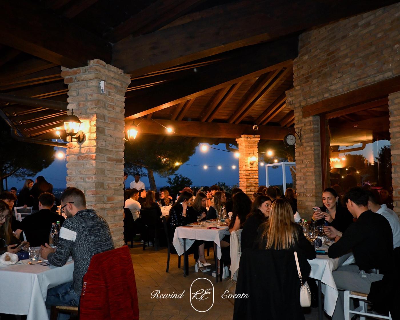 Ospiti a cena sotto un portico illuminato durante una serata REWIND